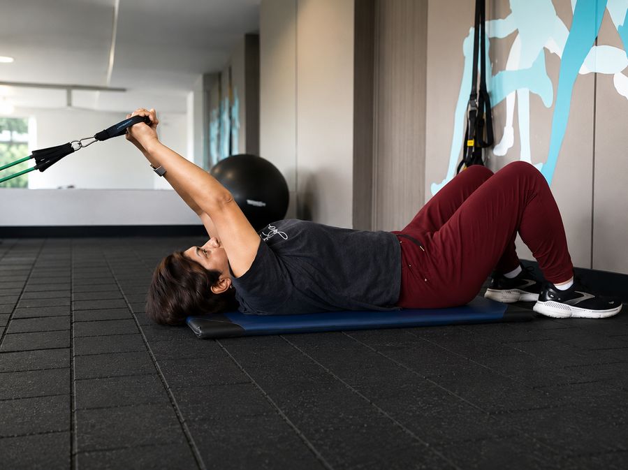 Mujer entrenando con bandas de resistencia en gimnasio siguiendo una rutina online